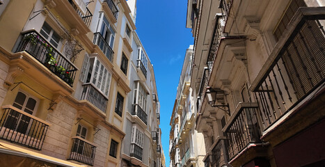 Narrow street with balconies stretching towards blue sky in Cadiz, Spain