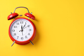 Red alarm clock on yellow background, top view. Space for text