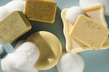 Soap bars with foam on grayish blue background, closeup