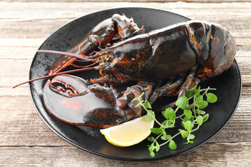 Raw lobster, piece of lemon and microgreens on wooden table, closeup