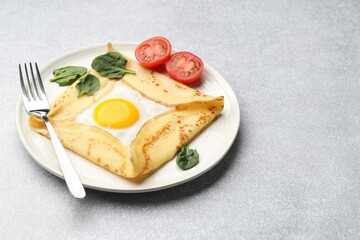 Delicious crepe with egg, tomato and basil on light grey table, closeup. Space for text
