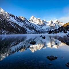 lake reflecting jagged snow-covered peaks with drifting 