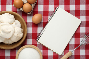 Blank recipe book, meringue cookies and ingredients on red checkered tablecloth, flat lay