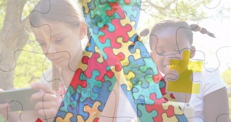 Image of colourful puzzle pieces ribbon over girls using tablets