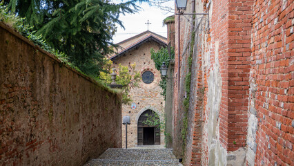 Ancient cobbled street leading to the 14th century church of San Giovanni, seat of the Servite Fathers on Via San Giovanni northern Italy, province of Cuneo, Piedmont, Italy..