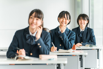 学校の教室で笑顔で授業を聞く制服姿の小学生・中学生・高校生・女子高生（友達）
