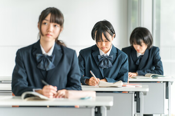 学校の教室で真剣に授業を受ける制服姿の小学生・中学生・高校生・女子高生（友達）
