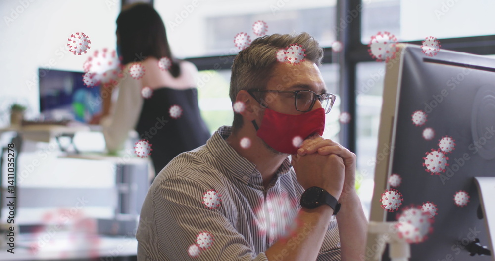 Poster image of covid 19 cells floating over man in face mask using computer in office
