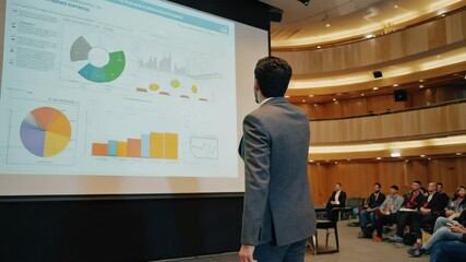 Speaker presenting charts at a business conference with audience, business professional presenting business information on a projector screen at presentation