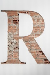 Artistic letter R cut through white plaster, exposing the red brick and mortar structure beneath