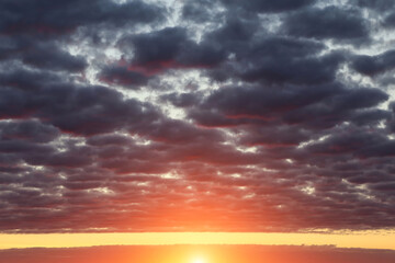 Epic dramatic sunset, sunrise on storm sky with dark fluffy cumulus clouds, orange yellow sun and sunlight abstract background texture