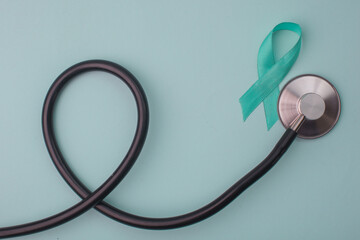 Teal Ribbon With Stethoscope On Light Blue Background. Symbolic for Cervical Cancer, Ovarian...