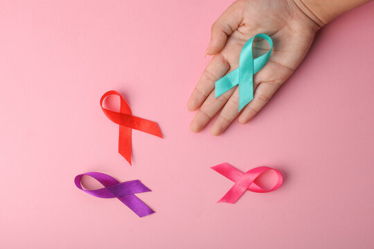 Teal Ribbon Put On Palm Hand Arrange With Red, Purple And Pink Ribbon To Support Cancer Survivor.