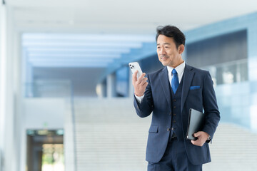 オフィスでスマホを見るミドルのビジネスマン