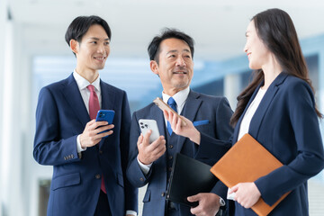オフィスでスマホを見る男女のビジネスマン