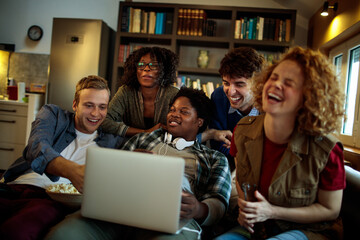 Young and diverse group of friends watching a movie on laptop in the living room on the couch