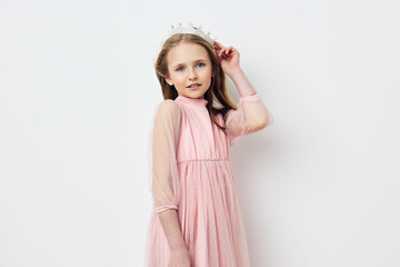 Young girl in a pink dress with a crown, smiling playfully, showcasing innocence and style against a soft white background Perfect for childhood and fashion concepts