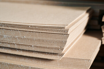 Stacks of thick paperboard ready for production of cardboard containers in an industrial setting...