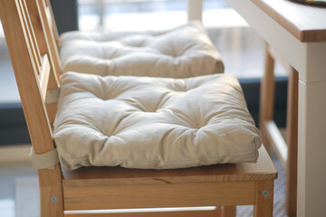 Cushioned wooden chairs at a modern dining table in sunlight