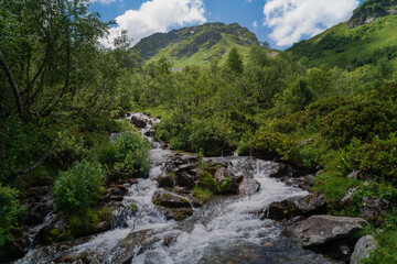 View of the Malaya Dukka River against the backdrop of the mountains of the North Caucasus on a sunny summer day, Arkhyz, Karachay-Cherkessia, Russia © Ula Ulachka