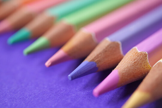 Vibrant colored pencils arranged on a purple background