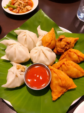 A plate of assorted chicken momos (steamed, fried and chilli sauce dumplings) served on a leaf plate at Tapari Nights, a Nepalese restaurant in Auburn, Sydney - NSW, Australia