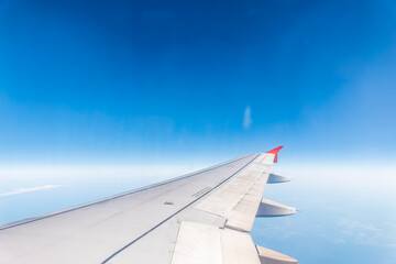 Fototapeta premium View from the airplane window at a beautiful cloudy sky and the airplane wing