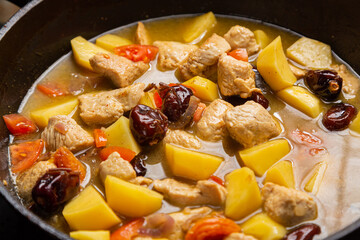 In a frying pan, chelnt is stewed with potatoes, onions, meat, spices and dates
