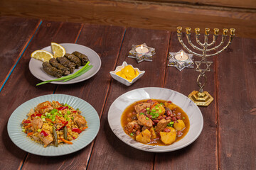 Menorah candles in candlesticks with the Star of David at the set table chelnt, bulgr dolma