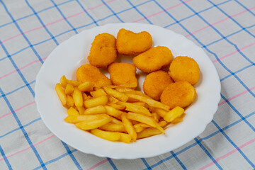 French fries and golden nuggets in a plate on a white checkered tablecloth