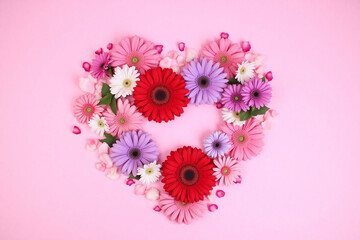 heart shaped arrangement of flowers on a pink background