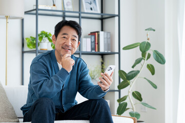 Naklejka premium リビングでスマホを使うミドルの男性