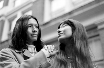 Fototapeta premium Young couple holding hands and looking up in urban setting, grainy monochrome film aesthetic