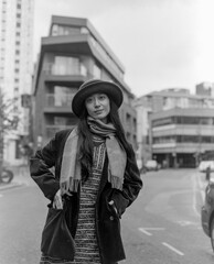 Stylish woman wearing hat and scarf posing in city street