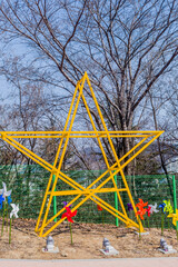  A large yellow star sculpture with trees in the background on a clear day.