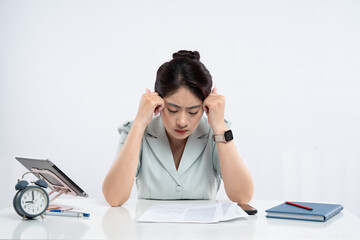 Stressed woman with hands on temples facing burnout at her desk with documents and devices