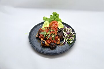 Indonesian grilled beef ribs smashed and served with spicy sambal. Iga Bakar Penyet is a flavorful traditional dish, often enjoyed with rice and fresh vegetables.