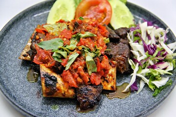 Indonesian grilled beef ribs smashed and served with spicy sambal. Iga Bakar Penyet is a flavorful traditional dish, often enjoyed with rice and fresh vegetables.