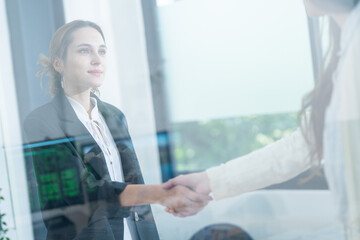 Professional handshake between two women in a modern office during a business meeting in the daytime