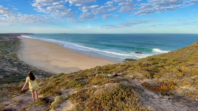 girl stands and admires long sandy beach between west cape lookout and Ethel Wreck Beach with powerful waves. Dhilba Guuranda-Innes National Park, Yorke Peninsula, south australia