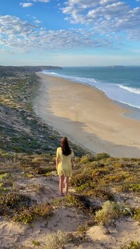girl stands and admires long sandy beach between west cape lookout and Ethel Wreck Beach with powerful waves. Dhilba Guuranda-Innes National Park, Yorke Peninsula, south australia