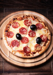 Pizza with salami and mozzarella cheese. Wooden background. Soft focus. Close up.	