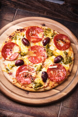 Pizza with chorizo ​​sausage, mozzarella and cheddar cheese, olive pesto and kalamata olives. Wooden background. Soft focus. Close up.	