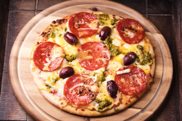 Pizza with chorizo ​​sausage, mozzarella and cheddar cheese, olive pesto and kalamata olives. Wooden background. Soft focus. Close up.	