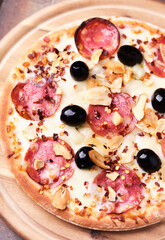 Pizza with salami and mozzarella cheese. Wooden background. Soft focus. Close up.	