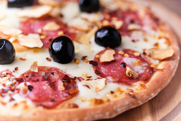 Pizza with salami and mozzarella cheese. Wooden background. Soft focus. Close up.	