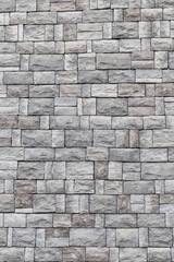 A brick wall made of natural granite cubes in a light grey tone, used as a background for graphic design.