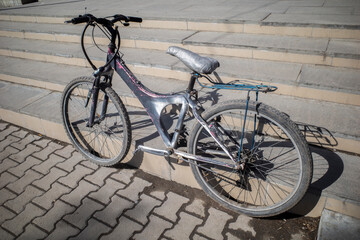 An old mountain bike is parked at the steps on a spring day