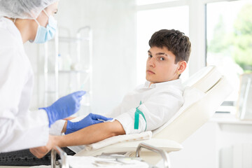 Obraz premium Anesthesiologist doctor injecting pain medication into vein of man before starting surgery in a cosmetology clinic