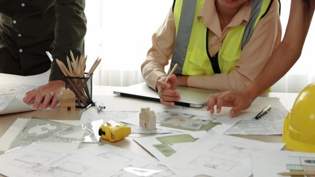 Professional engineer measuring the blueprint. Professional engineer working architectural project at studio on a table with yellow helmet and architectural equipment scatter around. Delineation.